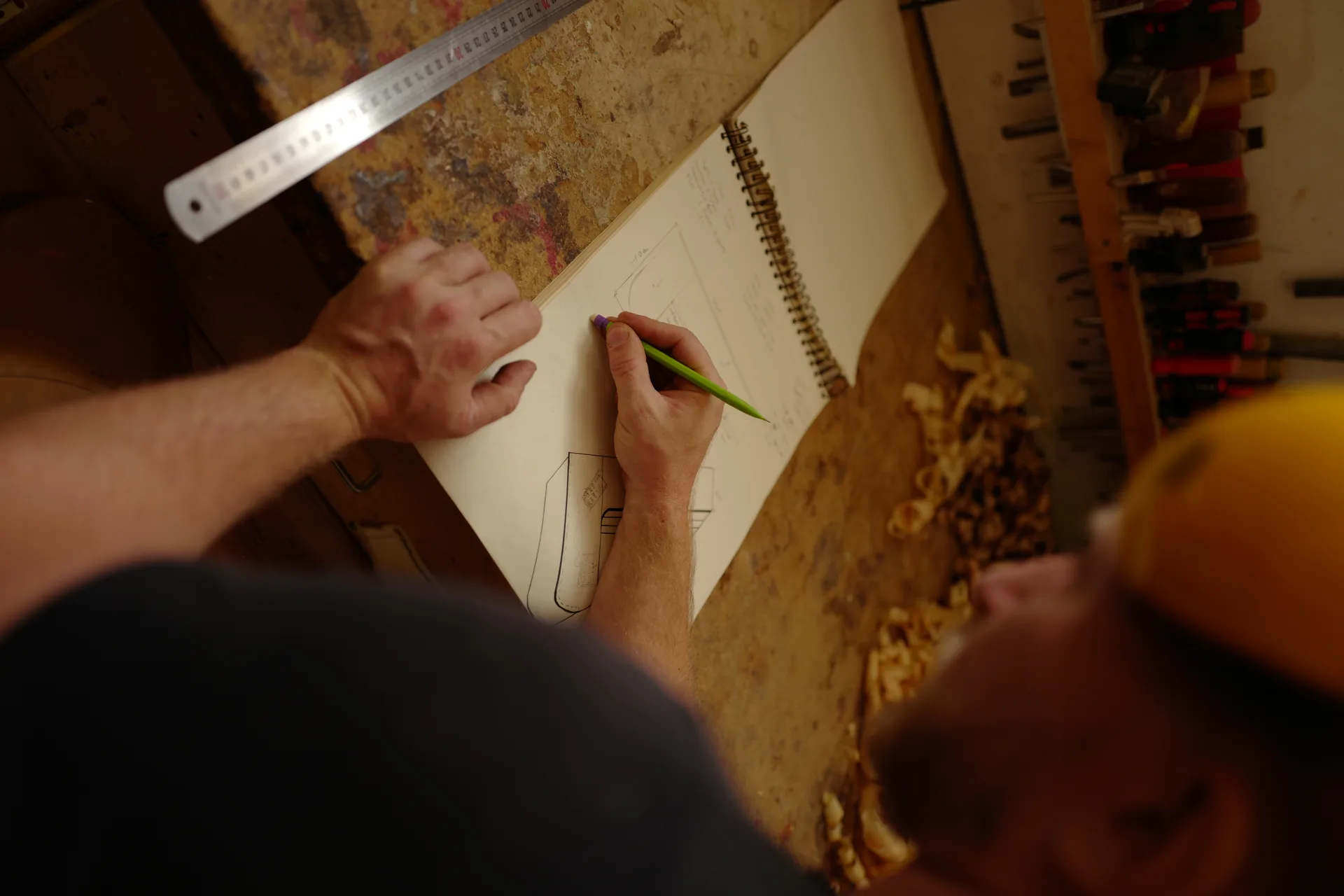 Théo Righi dessinant les plans d'un meuble à restaurer dans son atelier